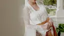 Potret lain memperlihatkan Syandria mengenakan kebaya kutubaru warna putih dengan selendang dan kain batik warna coklat. [Instagram/syandria]