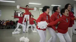 Suasana latihan anggota cheerleaders Cheer Mommy di ruang latihan di Samcheok, Korsel (3/3). Mereka mengenakan baju seragam merah lengkap dengan pom-pomnya melakukan gerakan layakanya pemandu sorak umumnya. (AFP/Ed Jones)