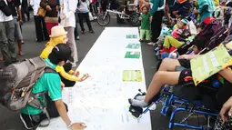 Masyarakat membubuhkan tanda tangan pada Peringatan Hari Cerebral Palsy Sedunia di area Car Free Day, Bundaran HI, Jakarta, Minggu (8/10). Kegiatan tersebut untuk menggalang kepedulian bagi penyandang Cerebral Palsy. (Liputan6.com/Angga Yuniar)