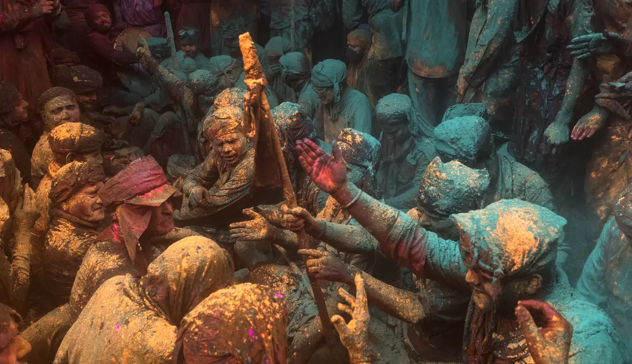 Umat Hindu mengambil bagian dalam pertemuan tradisional selama perayaan Lathmar Holi di sebuah kuil di Barsana, India, Selasa (23/3/2021). Baik pria, wanita, tua, muda, semuanya turun ke jalanan untuk memulai karnaval dengan saling melempar bubuk. (Xavier GALIANA/AFP)