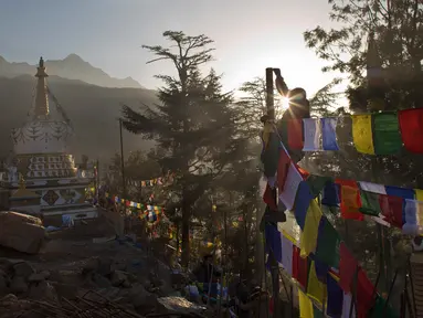 Seorang pria memasang bendera warna-warni atau yang disebut lungta pada hari ketiga Tahun Baru Tibet di Dharmsala, India (18/2). Bagi umat Buddha Tibet bendera itu berisi mantra yang mengandung doa. (AP/Ashwini Bhatia)