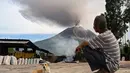 Warga menyaksikan Gunung Sinabung menyemburkan abu dan asap tebal dari wilayah Karo, Provinsi Sumatra Utara, Rabu, 2 September 2026. (AFP/ YT Haryono)