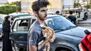 Seorang pemuda memeluk seekor kucing di dadanya saat orang-orang yang melarikan diri dari desa mereka di Lebanon selatan diterima di sebuah lembaga seni yang diubah menjadi tempat penampungan bagi para pengungsi akibat konflik, di Beirut pada 23 September 2024. (FADEL ITANI/AFP)