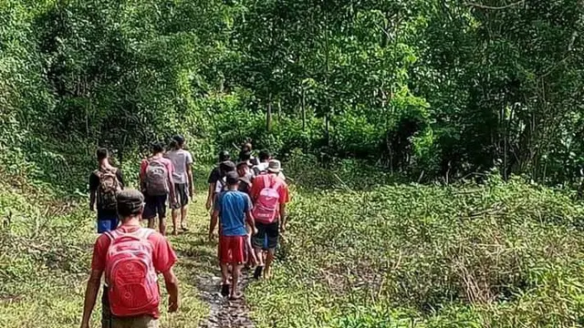 Para siswa dan guru menyusuri jalan tanah yang sempit di tengah-tengah hutan. (Foto Istimewah)