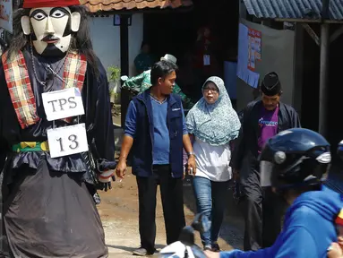 Boneka ondel-ondel tampak terpajang di pintu masuk TPS 13 Kelurahan Serua, Tangerang Selatan, Rabu (9/12). Jutaan warga Tangsel mengikuti hak suaranya untuk memilih 3 pasangan calon dalam Pilkada Serentak. (Liputan6.com/Fery Pradolo)