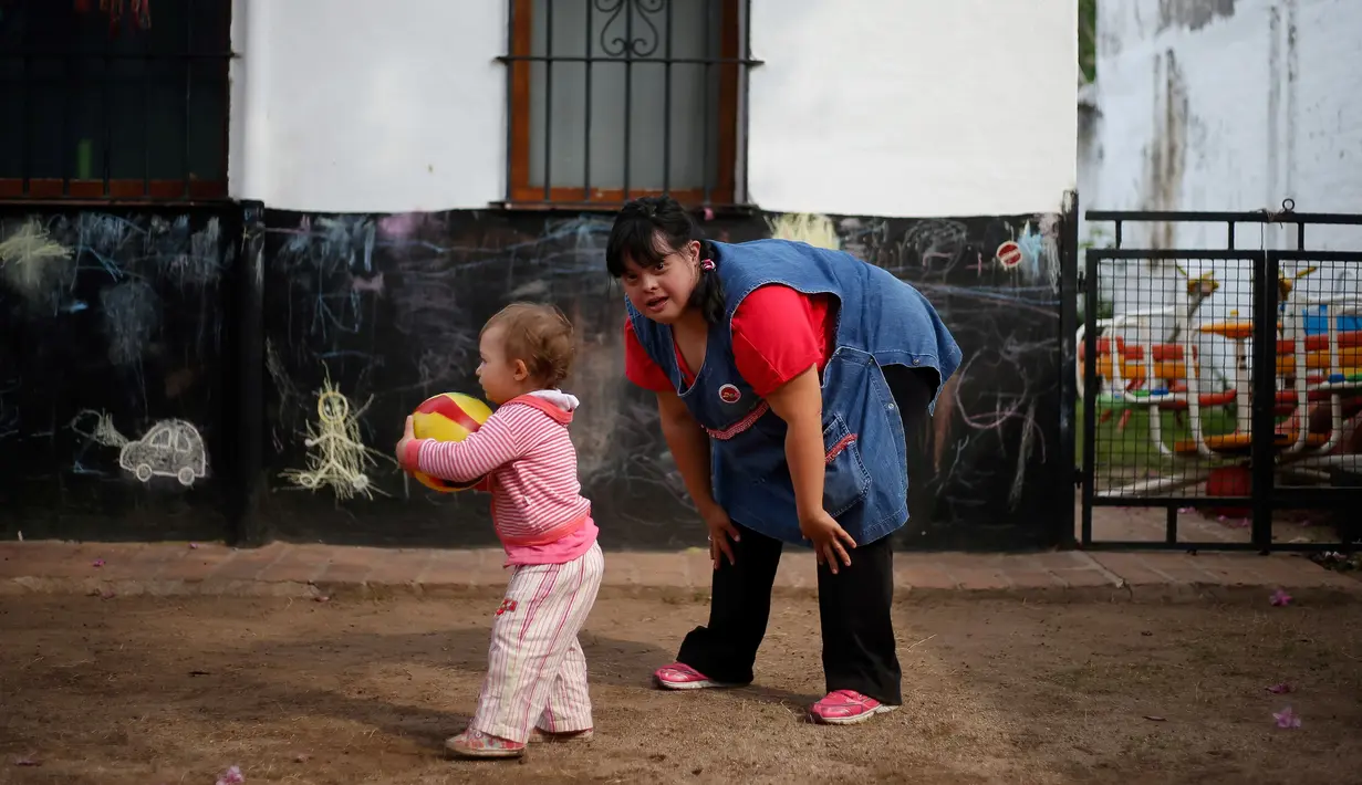 Noelia Garella bermain dengan seorang murid di TK Jeromito, Cordoba, Argentina (24/10). Noelia 31 tahun merupakan penderita down syndrome pertama yang menjadi guru TK. (AFP Photo/Diego Lima)