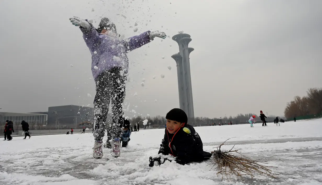 Anak-anak bermain salju di kanal beku di Taman Olimpiade Beijing di Beijing pada 20 Januari 2022. Ibu Kota China diselimuti salju pada Kamis, saat hitungan mundur menuju dua minggu Olimpiade Musim Dingin Beijing 2022 dimulai. (Noel Celis / AFP)