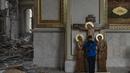 Seorang anak laki-laki mencium patung Yesus saat membantu membersihkan Katedral Transfigurasi Odesa setelah gereja rusak berat akibat serangan rudal Rusia di Odesa, Ukraina, Minggu, 23 Juli 2023. (AP Photo/Jae C. Hong)