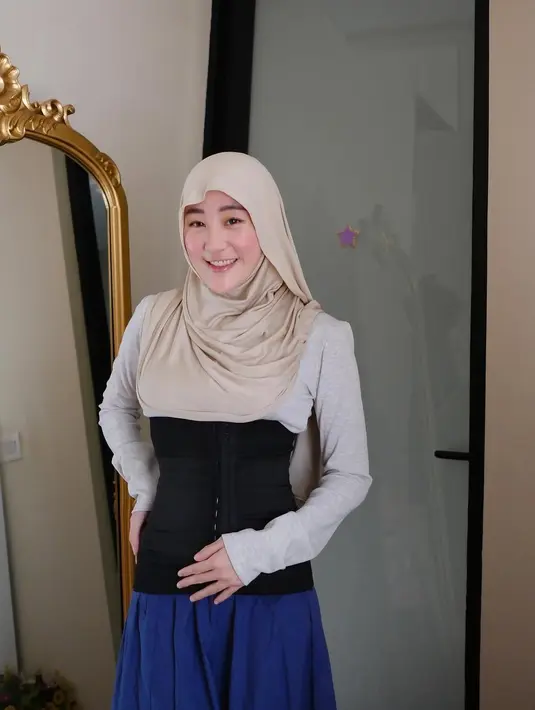Tidak hanya tampil fashionable saat beraktivitas di luar rumah, Larissa juga menunjukkan perubahan bentuk tubuhnya usai melahirkan. Dalam sebuah potret lainnya, ia tampak mengenakan hijab beige dengan busana simpel berupa baju lengan panjang abu-abu dan rok navy. Hal yang paling mencuri perhatian adalah korset hitam yang dikenakannya, menandakan usahanya untuk kembali ke bentuk tubuh ideal.  (Liputan6.com/IG/@larissachou)