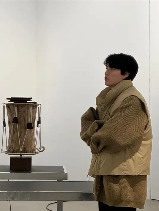 Ryu Jun Yeol tampil dengan outfit yang dilayering. Ia mengenakan jaket cokelat oversized masih ditumpuknya dengan vest cokelat yang senada, dan padu padan mengenakan celana panjang hitam. [Foto: Instagram/ryusdb]