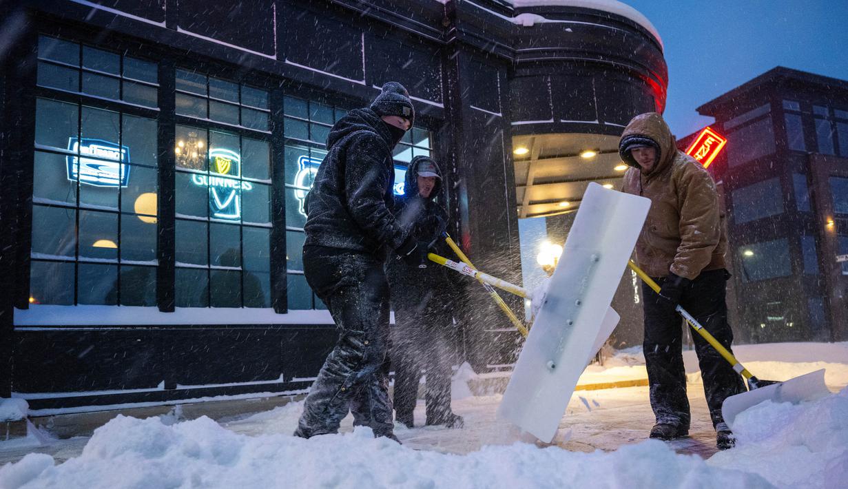 Seorang pria menyekop salju dari trotoar di Ankeny, Iowa, pada tanggal 12 Januari 2024. (Jim WATSON/AFP)
