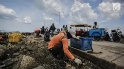 Petugas kebersihan membersihkan sampah laut di Pelabuhan Kali Adem, Jakarta, Senin (1/1). Banyaknya sampah plastik dibandingkan ikan yang gagal dikelola dengan baik membuat limbah yang mengakibatkan laut tercemar.  (Liputan6.com/Faizal Fanani)