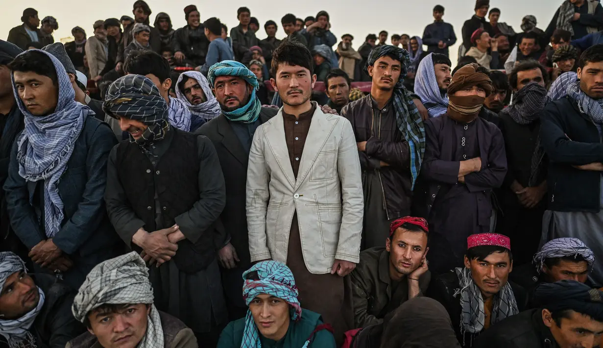Warga Afghanistan menyaksikan peserta bergulat selama tontonan gulat mingguan yang diadakan di arena darurat di taman Chaman-e-Hozori, di Kota Kabul (12/11/2021). (AFP/Hector Retamal)