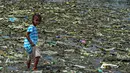 Seorang anak perempuan berjalan di tumpukan sampah di permukiman kumuh di sepanjang garis pantai Pantai Baseco di Manila (28/9/2019). Pada 12 Februari 2002, Presiden Gloria Macapagal Arroyo menyatakan Baseco sebagai tempat tinggal.  (AFP Photo/Maria Tan)