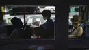 Komuter duduk di dalam bus menjelang Olimpiade Musim Panas 2020, di Tokyo pada 16 Juli 2021. Di bawah protokol yang ketat, satu-satunya cara untuk melihat sekilas ibu kota adalah dari kendaraan yang mengantar para tamu dari perkampungan atlet atau hotel ke venue. (AP Photo/Jae CHong)