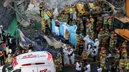Tim SAR mencari korban di antara puing-puing bangunan yang runtuh di Gwangju, Korea Selatan (9/6/2021).  Sedikitnya 9 orang tewas dan 8 terluka akibat sebuah gedung lima lantai runtuh tiba-tiba ketika sedang dalam proses pembongkaran. (AFP/Yonhap)