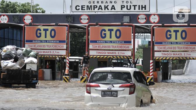 Mobil nekat menerobos banjir menuju Gerbang Tol Cempaka Putih, Jakarta, Minggu (23/2/2020). Banjir yang melanda kawasan tersebut menyebabkan Gerbang Tol Cempaka Putih tidak dioperasikan akibat terendam hingga ketinggian mencapai sepinggang orang dewasa. (merdeka.com/Iqbal S. Nugroho)