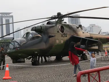 Warga berfoto berlatar helikopter TNI pada pameran Alat Utama Sistem Persenjataan TNI di Kawasan Monas, Jakarta, Kamis (27/9). Pameran ini bagian perayaan HUT TNI ke-73. (Liputan6.com/Helmi Fithriansyah)
