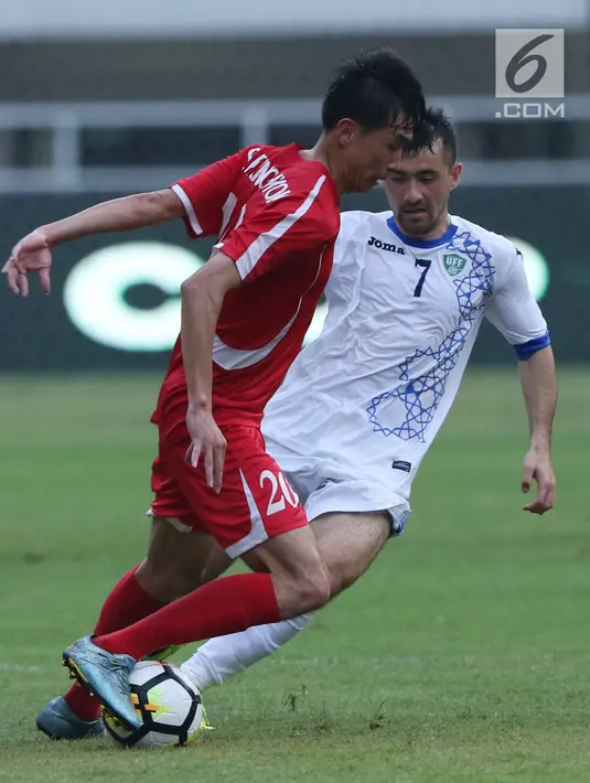 Gelandang Uzbekistan, Tukhtasinov Nurilio berebut bola dengan pemain Korea Utara pada laga perdana PSSI Anniversary 2018 di Stadion Pakansari, Kab Bogor, Jumat (27/4). Laga berakhir imbang 2-2. (Liputan6.com/Helmi Fithriansyah)