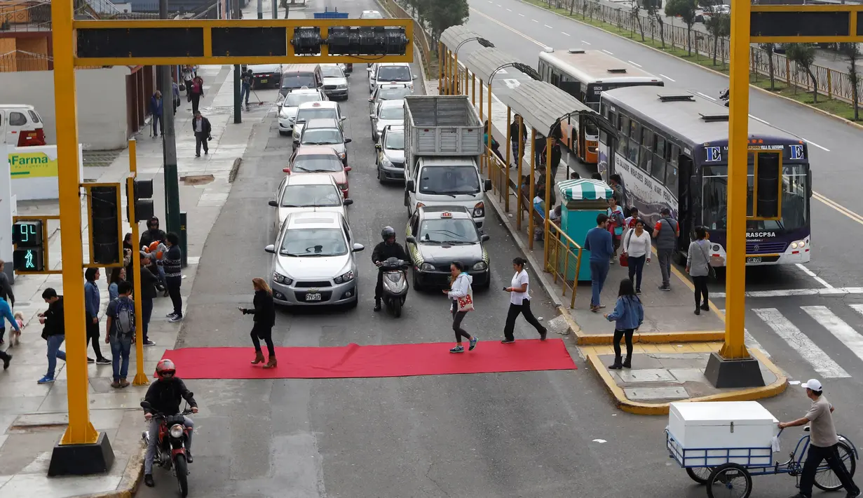 Sebum karpet merah terbentang di salah satu ruas jalan di distrik Magdalena del Mar, Lima, Peru, Sabtu (2/7). Aksi tersebut dilakukan untuk pejalan kaki agar bisa menyeberang dengan nyaman. (REUTERS / Guadalupe Pardo)