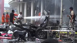 Petugas pemadam kebakaran mencoba memadamkan api setelah serangan bom mobil di sebuah supermarket di Kota Pattani, Thailand (10/5). Ledakan bom mobil tersebut mengakibatkan puluhan orang terluka. (AP Photo)