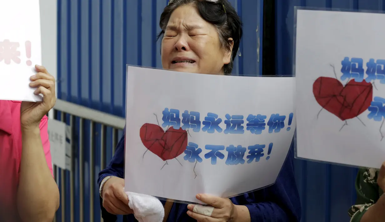 Salah satu keluarga penumpang MH370 menangis saat menggelar aksi di depan kantor Malaysia Airlines, Beijing, China, Kamis (6/8). Pemerintah Malaysia telah resmi menyatakan puing pesawat di Pulau Reunion adalah bagian dari MH370. (REUTERS/Jason Lee)