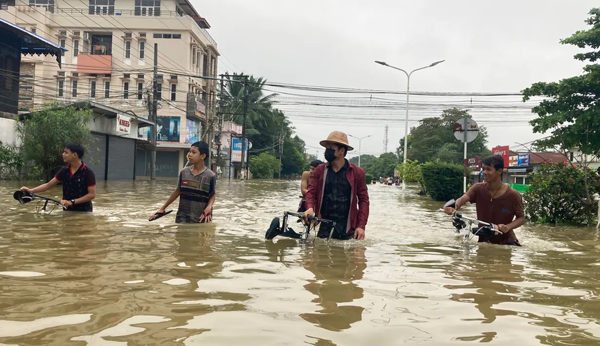 Penduduk setempat menyeberangi jalan yang banjir di Bago, sekitar 80 kilometer (50 mil) timur laut Yangon, Myanmar, Senin (9/10/2023). Banjir yang dipicu oleh hujan lebat di wilayah selatan Myanmar telah menyebabkan lebih dari 10.000 orang mengungsi dan mengganggu lalu lintas di jalur kereta api yang menghubungkan kota-kota terbesar di negara itu, kata para pejabat dan media pemerintah pada hari Senin. (AP Photo/Thein Zaw)