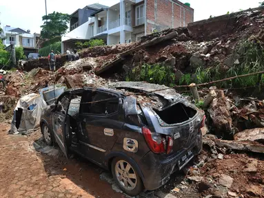 Sebuah mobil rusak setelah tertimpa material longsor tembok perumahan Lereng Indah di Perumahan Lereng Bukit Indah, Pondok Cabe Udik, Pamulang,Tangerang Selatan, Senin (8/4). Dua mobil warga perumahan Lereng Indah rusak tertimpa longsor saat hujan deras. (merdeka.com/Arie Basuki)