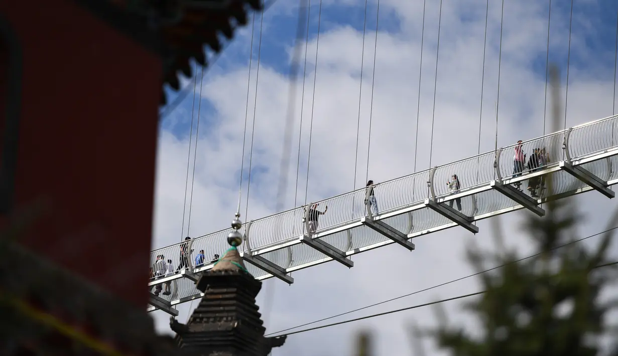 Wisatawan berjalan di atas jembatan gantung berlantai kaca di kawasan wisata nasional Hongshiya di Wilayah Zhuozi, Ulanqab, Daerah Otonom Mongolia Dalam, China utara, pada 15 Agustus 2020. (Xinhua/Peng Yuan)