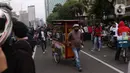 Pedangang menawarkan dagangannya kepada massa aksi saat demo penolakan omnibus law di kawasan patung kuda, Jakarta, Selasa (20/10/2020). Para pedagang kaki lima memanfaatkan moment aksi massa untuk mencari ke untungan meskupun sangat membahayakan bagi keselamatan mereka. (Liputan6.com/Angga Yuniar)