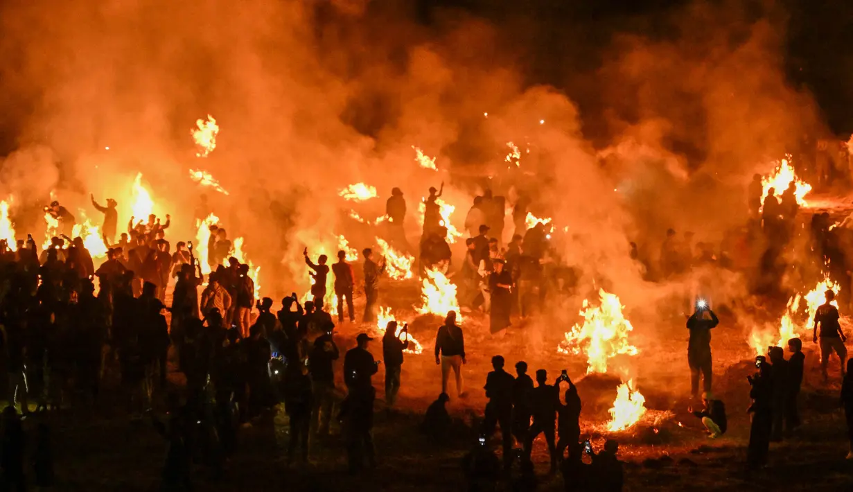 Foto diambil pada 1 Oktober 2023 saat beberapa orang masuk ke dalam stadion dan menyalakan api di lapangan untuk memberikan penghormatan kepada para 135 korban tragedi stadion Kanjuruhan Malang setahun lalu. (Juni Kriswanto/AFP)
