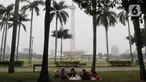 Pengunjung beristirahat sambil menikmati suasana kawasan Monas, Jakarta, Selasa (26/12/2023). (merdeka.com/Imam Buhori)