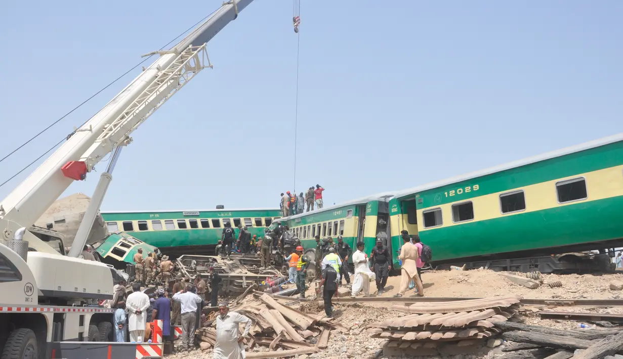 Alat berat dikerahkan untuk mengevakuasi gerbong dalam kecelakaan dua kereta di distrik Rahim Yar Khan, Pakistan, Kamis (11/7/2019). Insiden ini menyebabkan setidaknya sembilan orang tewas dan lebih dari 60 lainnya luka-luka. (AP Photo/Waleed Saddique)