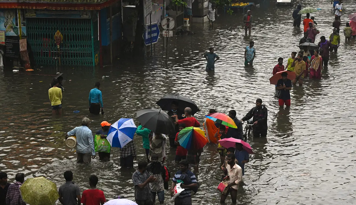 Orang-orang mengarungi jalan yang banjir setelah hujan lebat di Chennai, India (8/11/2021). Chennai dilanda Curah Hujan Terberat Sejak 2015,  Pihak berwenang Keluarkan Peringatan Banjir. (AFP/Arun Sankar)