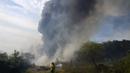 Seorang petugas pemadam kebakaran sukarela menggunakan tusukan dari selang untuk membasahi sisa-sisa gubuk yang terbakar selama kebakaran semak di lingkungan Banco San Miguel di Asuncion, Paraguay (18/1/2022). (AP Photo/Jorge Saenz)