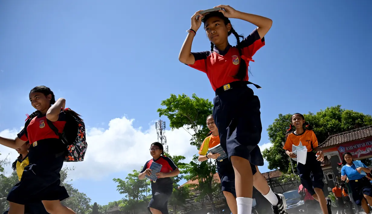 Sejumlah pelajar berlari saat mengambil bagian dalam latihan simulasi gempa bumi dan tsunami di Jimbaran, Bali (5/11/2019). Latihan dilakukan untuk memberikan pengajaran kepada siswa agar mengantisipasi bahaya bencana gempa bumi dan tsunami yang bisa datang sewaktu-waktu. (AFP Photo/Sonny Tumbelaka)