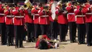 Seorang trombonis militer yang pingsan tampaknya berusaha untuk terus bermain setelah jatuh ke tanah saat petugas medis bergegas membantunya. (AP Photo/Alberto Pezzali)