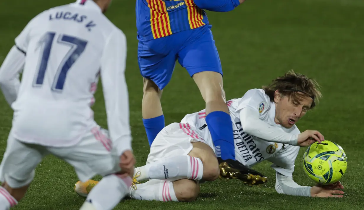 Gelandang Real Madrid, Luka Modric terjatuh saat berebut bola dengan penyerang Barcelona, Pedri pada pekan ke-30 Liga Spanyol di Estadio Alfredo Di Stefano, Minggu dinihari WIB (11/4/2021). Real Madrid kembali sukses taklukkan rival abadinya Barcelona 2-1. (AP Photo/Manu Fernandez)