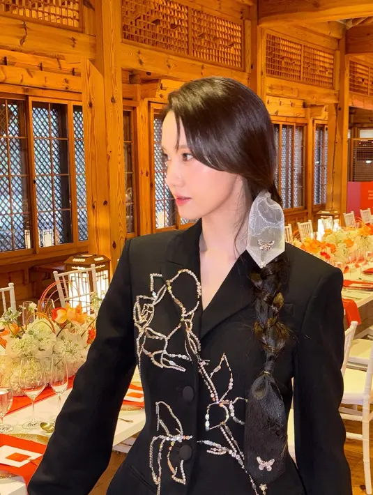 Rambut panjang Yoona ditata dengan kepang samping menggunakan pita. Sisakan poni tanggung yang ciptakan messy look [@yoona__lim]