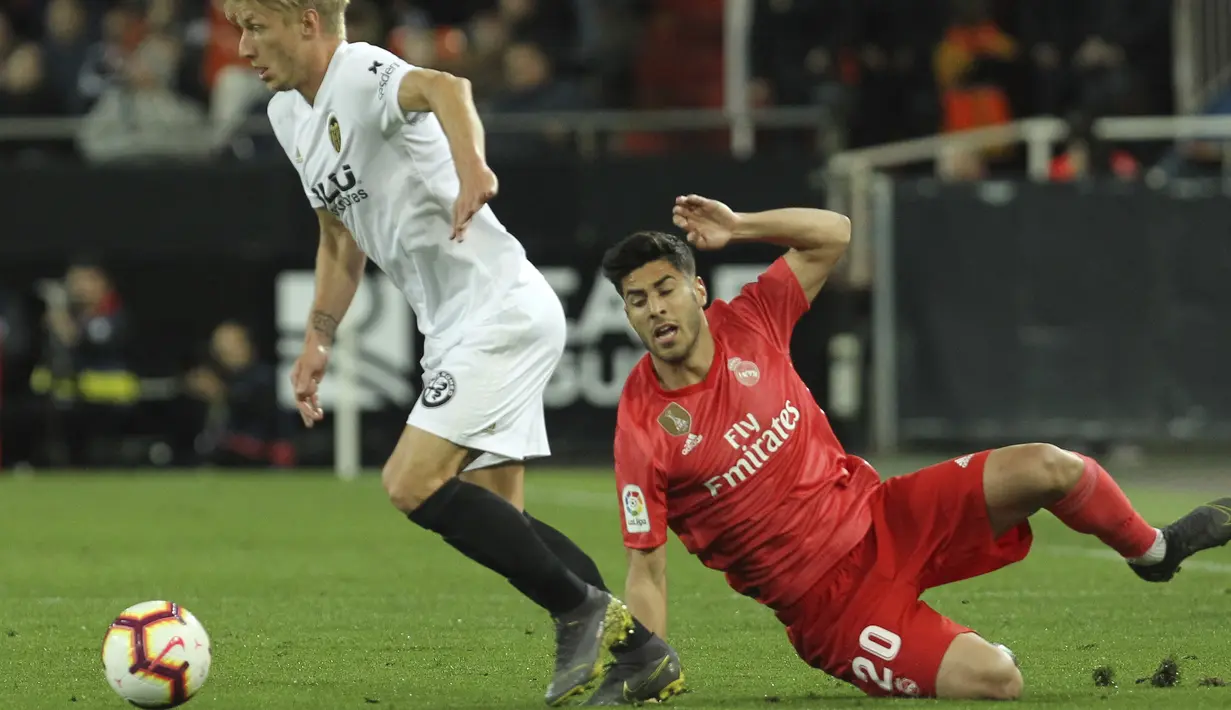 Gelandang Real Madrid, Marco Asensio, terjatuh saat berebut bola dengan pemain Valencia, Daniel Wass, pada laga La Liga 2019 di Stadion Mestalla, Rabu (3/4). Valencia menang 2-1 atas Real Madrid. (AP/Alberto Saiz)