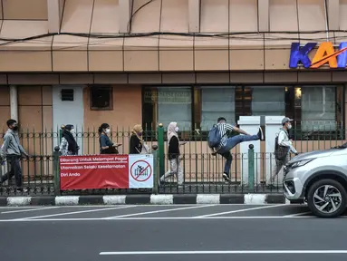 Calon penumpang kereta Commuter Line (KRL) melompati pagar saat hendak menuju Stasiun Cikini, Jakarta Pusat, Kamis (25/5/2023). (merdeka.com/Iqbal S.Nugroho)