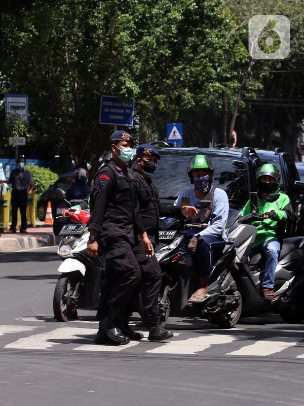 Dua polisi menyeberang jalan saat berjaga di sekitar Pengadilan Negeri Jakarta Selatan, Senin (4/1/2021). Pengamanan ratusan aparat kepolisian dilakukan untuk mengantisipasi pergerakan masa pada saat sidang praperadilan Rizieq Shihab. (Liputan6.com/Angga Yuniar)