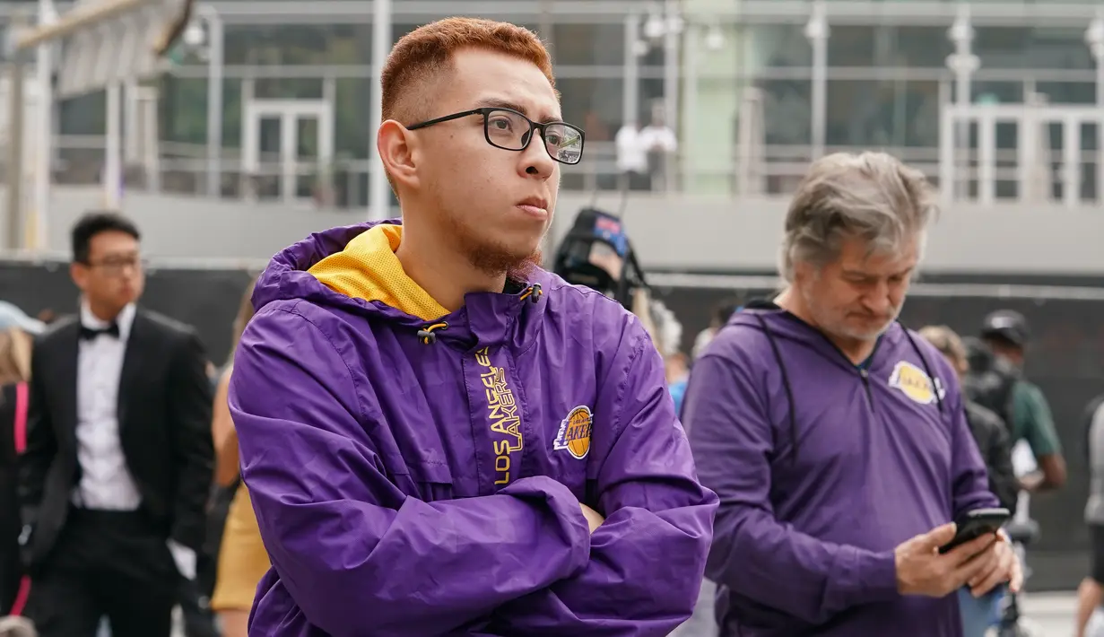 Fans LA Lakers tampak sedih usai Kobe Bryant meninggal dunia di Staples Center, Minggu (26/1/2020). Legenda basket NBA itu wafat dalam kecelakaan helikopter di Calabasas, California. (AFP/Rachel Luna)