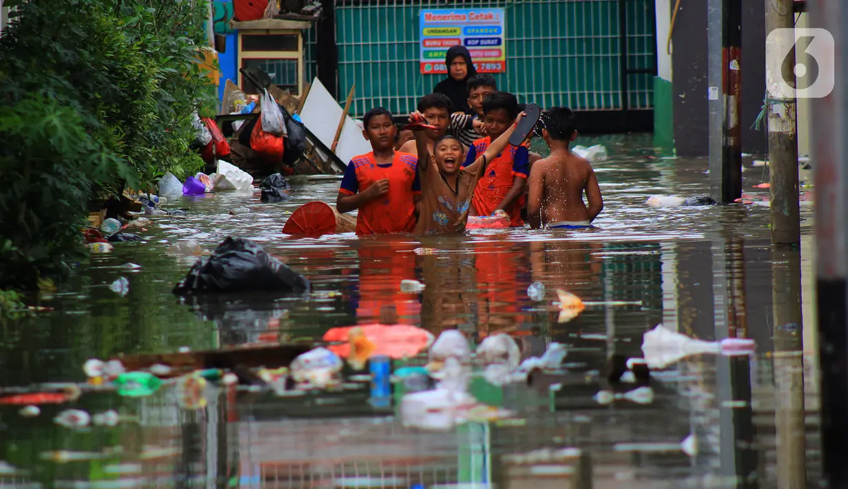 Sejumlah anak bermain banjir yang merendam kawasan Kampung Melayu Kecil, Bukit Duri, Jakarta, Selasa (25/2/2020). Banjir tersebut akibat luapan sungai Ciliwung. (merdeka.com/magang/ Muhammad Fayyadh)