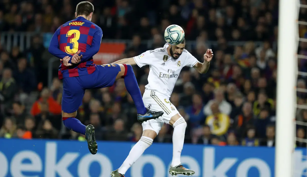 Penyerang Real Madrid, Karim Benzema menyundul bola dari kawalan bek Barcelona, Gerard Pique pada pertandingan lanjutan La Liga Spanyol di stadion Camp Nou (18/12/2019). Barcelona bermain imbang 0-0 atas Real Madrid. (AP Photo/Joan Monfort)