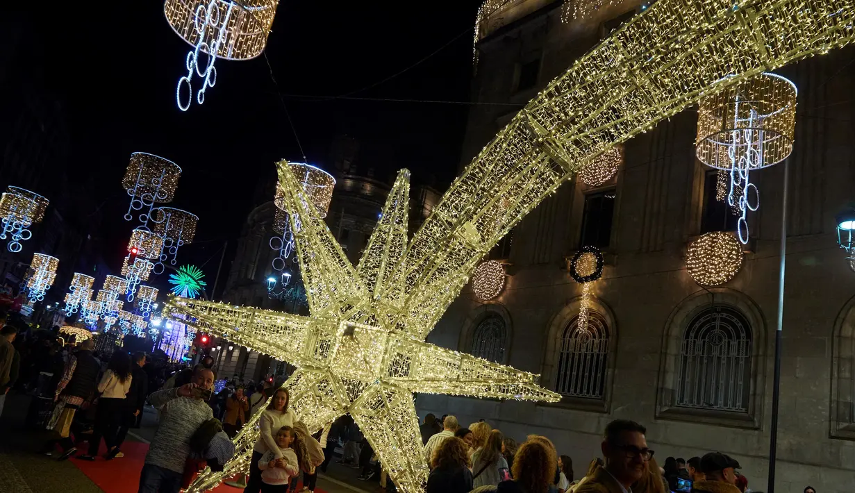 Orang-orang berfoto di bawah lampu-lampu Natal di pusat kota Vigo, barat laut Spanyol, pada 16 November 2024. (MIGUEL RIOPA/AFP)
