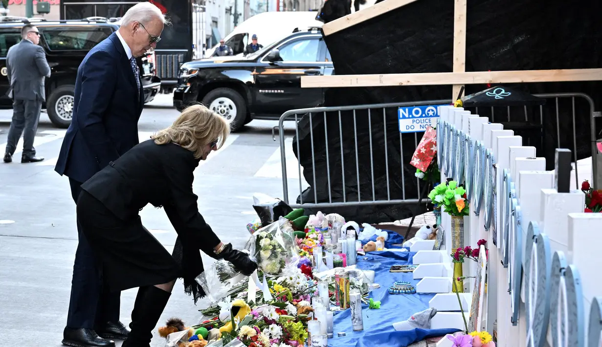Ibu Negara Jill Biden terlihat meletakkan karangan bunga di lokasi sesaat sebelum keduanya menundukkan kepala untuk mengheningkan cipta. (ROBERTO SCHMIDT/AFP)