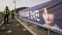 Petugas polisi Korea Selatan melewati spanduk yang menunjukkan gambar member grup K-Pop BTS, Jin di dekat pusat pelatihan tentara di Yeoncheon, Selasa (13/12/2022). Kim Seok-jin atau yang lebih dikenal dengan nama Jin BTS memulai wajib militer pada hari Selasa 13 Desember 2022 ini. (AP Photo/Ahn Young-joon)