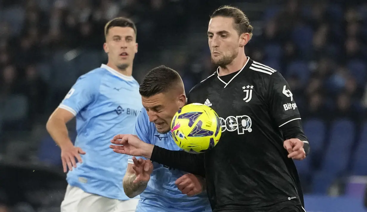 Gelandang Lazio, Mattia Zaccagni (tengah) berebut bola dengan gelandang Juventus, Adrien Rabiot pada laga pekan ke-29 Liga Italia 2022/2023 di Olimpico Stadium, Roma, Minggu (9/4/2023) dini hari WIB. (AP Photo/Alessandra Tarantino)