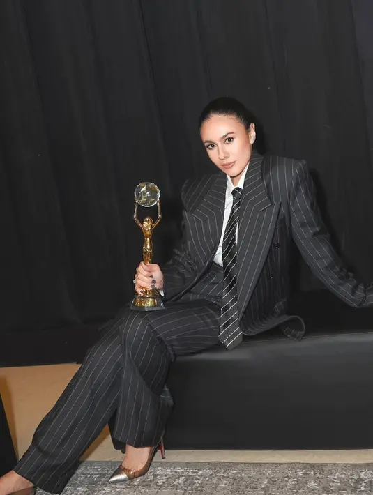 Ibu 4 anak itu lengkapi busana maskulinnya dengan dasi bergaris dan heels silver Christian Louboutin [@wulanguritno]